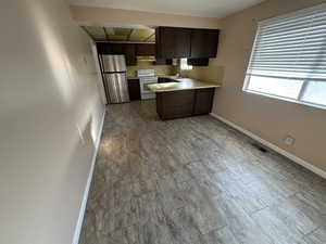 Kitchen with sink, stainless steel fridge, light wood-type flooring, white electric range oven, and dark brown cabinets