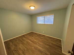 Spare room featuring dark wood-type flooring