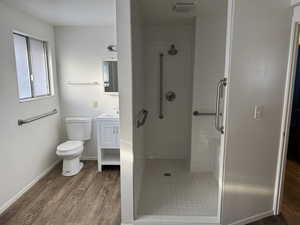 Bathroom with hardwood / wood-style floors, vanity, toilet, and tiled shower