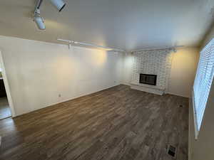 Unfurnished living room featuring a fireplace, dark hardwood / wood-style flooring, and track lighting