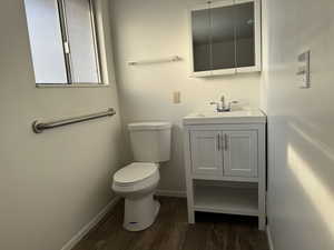 Bathroom with hardwood / wood-style floors, vanity, and toilet