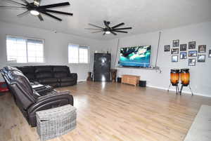 Living room with ceiling fan, wood-type flooring, and a textured ceiling