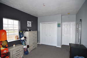 Carpeted bedroom with a textured ceiling and a closet