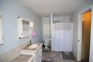 Bathroom with walk in shower, vanity, a textured ceiling, and toilet