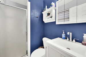 Bathroom featuring vanity, toilet, and a shower with shower door