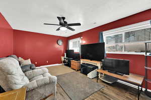 Living room featuring wood-type flooring, a textured ceiling, and ceiling fan