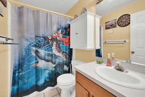 Bathroom with tile patterned floors, curtained shower, vanity, and toilet