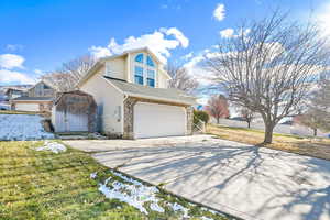 View of front of house featuring a garage, a front yard, and a storage shed