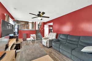 Living room with ceiling fan, wood-type flooring, and a textured ceiling