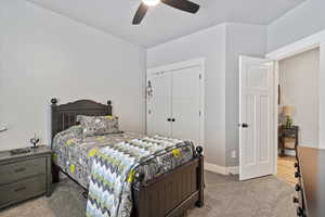 Carpeted bedroom with a closet and ceiling fan