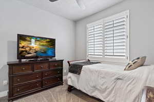 Bedroom featuring light carpet, a textured ceiling, and ceiling fan