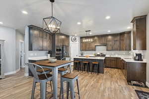 Kitchen with dark brown cabinetry, a center island, sink, light hardwood / wood-style floors, and decorative light fixtures