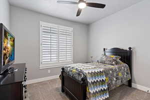 Carpeted bedroom featuring a textured ceiling and ceiling fan