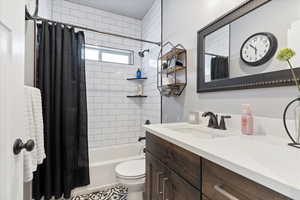 Full bathroom with vanity, shower / bath combination with curtain, and toilet