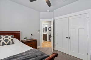 Carpeted bedroom featuring ceiling fan, a textured ceiling, and a closet