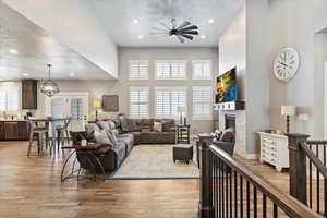 Living room with a high ceiling, ceiling fan, light hardwood / wood-style floors, and a textured ceiling