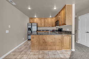 Kitchen featuring sink, kitchen peninsula, stainless steel appliances, and dark stone counters