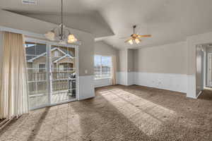 Interior space featuring ceiling fan with notable chandelier, carpet floors, and vaulted ceiling