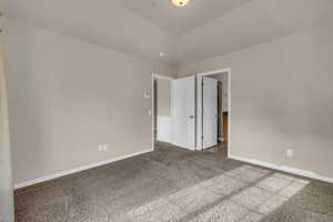 Carpeted empty room featuring vaulted ceiling