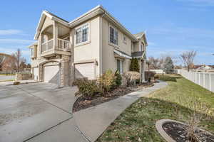 View of side of home featuring a lawn, a balcony, and a garage