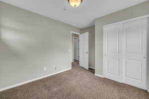 Unfurnished bedroom with light carpet and a closet