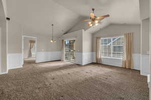 Carpeted empty room featuring ceiling fan with notable chandelier and lofted ceiling