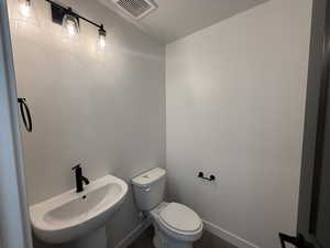 Bathroom featuring wood-type flooring, a textured ceiling, toilet, and sink