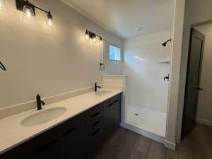 Bathroom featuring vanity, wood-type flooring, a textured ceiling, and walk in shower