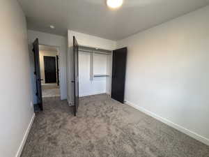 Unfurnished bedroom featuring carpet flooring, a textured ceiling, and a closet