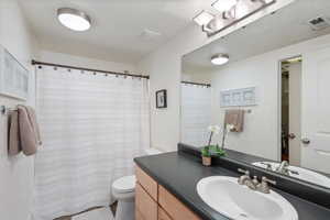 Full bath featuring toilet, visible vents, and vanity