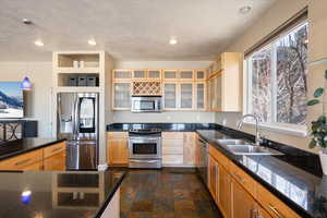 Kitchen with stainless steel appliances, recessed lighting, glass insert cabinets, stone finish floor, and a sink