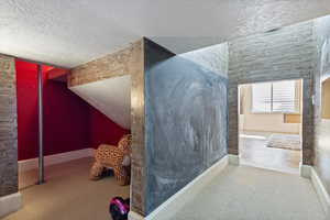 Interior space featuring a textured ceiling, carpet floors, lofted ceiling, and baseboards