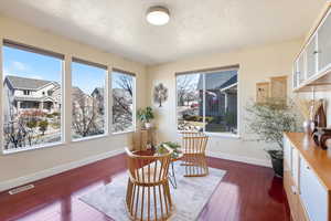 Living area featuring dark wood-style flooring, visible vents, and baseboards