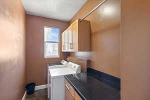 Washroom featuring cabinet space, washing machine and clothes dryer, and baseboards