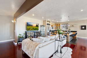 Living room featuring a textured ceiling, dark wood-style flooring, recessed lighting, and baseboards