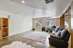 Living room featuring baseboards, visible vents, concrete flooring, and recessed lighting