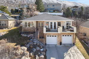 View of front of property with a mountain view, a garage, concrete driveway, french doors, and roof with shingles