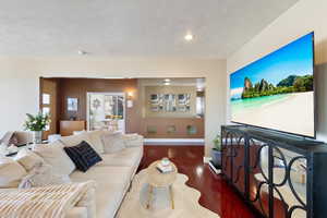 Living room with a textured ceiling, baseboards, and hardwood / wood-style floors