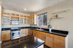 Kitchen with tile counters, glass insert cabinets, stainless steel appliances, a sink, and recessed lighting