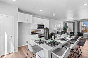 Kitchen with white cabinetry, sink, a breakfast bar area, appliances with stainless steel finishes, and light wood-type flooring