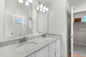 Bathroom featuring tiled shower, vanity, and tile patterned flooring