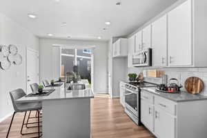 Kitchen featuring white cabinetry, a breakfast bar, stainless steel appliances, and light wood-type flooring