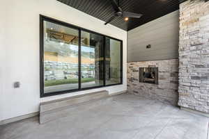 View of patio / terrace with an outdoor stone fireplace and ceiling fan