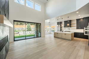 Great room featuring a kitchen island with sink, plenty of natural light, and a towering ceiling