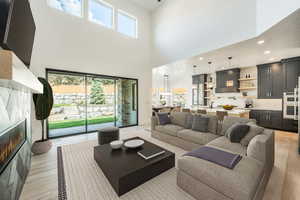 Greaty room featuring a towering ceiling, light hardwood / wood-style flooring, and a tiled fireplace