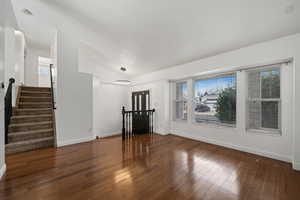 Unfurnished living room featuring lofted ceiling and dark wood-type flooring