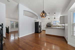 Kitchen featuring light stone countertops, white cabinetry, stainless steel appliances, dark hardwood / wood-style flooring, and pendant lighting