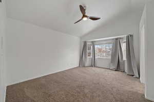 Unfurnished room featuring carpet flooring, ceiling fan, and lofted ceiling