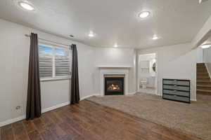 Unfurnished living room featuring a textured ceiling and dark hardwood / wood-style floors