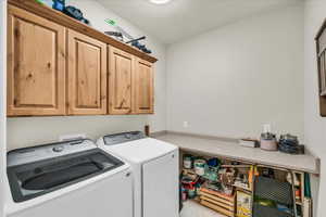 Laundry room with light tile patterned flooring, cabinets, and independent washer and dryer